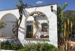 een wit gebouw met een gewelfd raam en planten bij Cortijo Pura Vida in Cómpeta