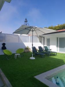 eine Liegewiese mit Stühlen, einem Sonnenschirm und einem Pool in der Unterkunft Lavra Beach House in Lavra