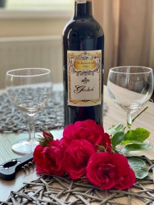 a bottle of wine and red roses on a table at Apartamenty W Brzozowym Gaju in Kudowa-Zdrój