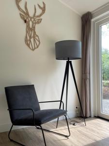 a chair and a lamp in a room with a window at Bok's Bungalowpark in Garderen