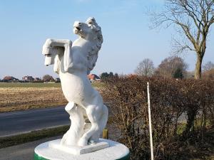 a statue of a white horse on the side of a road at Steinhaus Hof in Bunde