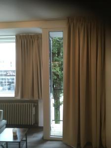 een woonkamer met een groot raam met gordijnen bij Residentie Jan Bart in Oostende +3 foto's