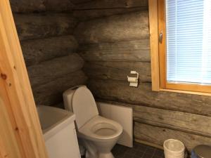 a bathroom with a toilet and a wooden wall at Kojamopirtit in Kolari