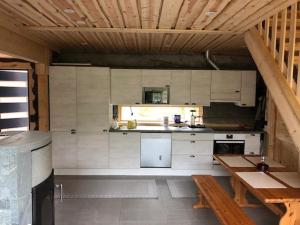 a kitchen with white cabinets and a wooden ceiling at Kojamopirtit in Kolari