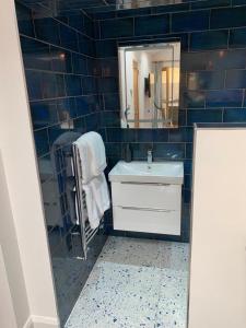 Baño de azulejos azules con lavabo y espejo en The Forge Guest Rooms en Long Whatton