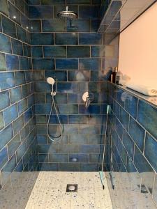 y baño con ducha de azulejos azules y cabezal de ducha. en The Forge Guest Rooms, en Long Whatton