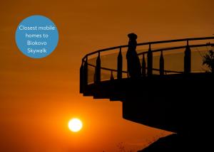 una sagoma di una persona in piedi su una scala al tramonto di Medora Orbis Mobile Homes & Glamping a Podgora
