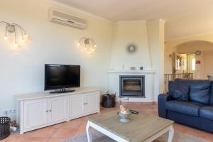 ein Wohnzimmer mit einem TV, einem Sofa und einem Tisch in der Unterkunft Luxury Townhouse n10 - Front-line Sea views in Ferragudo