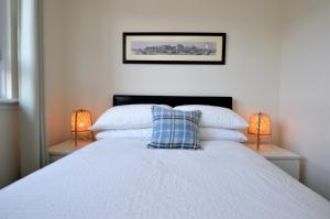 a bedroom with a white bed with two lamps at Bishop's Snug in Dunoon