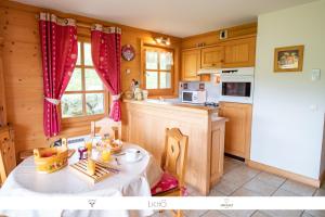 een keuken met een tafel en een keuken met houten kasten bij Sur Le Feug Appt 14 in Combloux