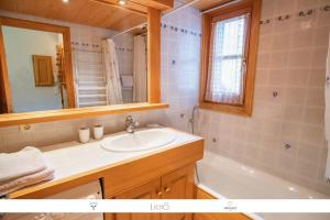 een badkamer met een wastafel, een bad en een spiegel bij Sur Le Feug Appt 14 in Combloux