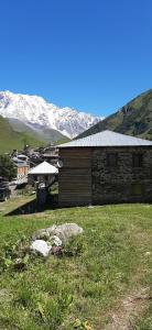 a building in a field with mountains in the background at Guesthouse and restaurant SVANURI SAKHLI in Ushguli