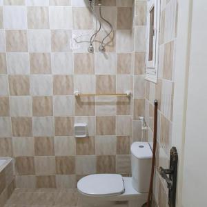 a small bathroom with a toilet and a shower at Sweet Home Hostel - ممنوع للبنات المصرين in Hurghada +13 photos