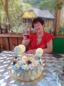 una mujer sosteniendo una copa de vino delante de un pastel en Стаи за гости Тамара, en Ezerets