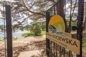 a sign on a gate with a view of a lake at Marina Kociewska in Ocypel