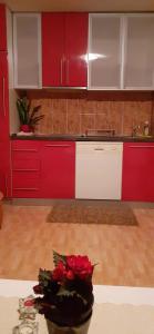 a kitchen with red and white cabinets and a vase of roses at Apartmani Becic in Sutomore