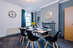 ein Esszimmer mit einem Tisch, Stühlen und einer Uhr in der Unterkunft Ideal for CONTRACTORS & WORKERS, Long-term discounts - 4-Bed House in Crewe by 53 Degrees Property - Sleeps 8 in Crewe