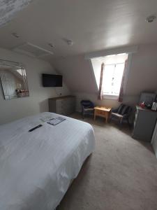 a bedroom with a large white bed and a living room at The Redcliff in Weymouth