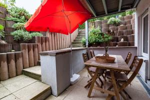 - une table et des chaises avec un parasol rouge sur la terrasse dans l'établissement Ruhiges Apartment Ettlingen, à Ettlingen