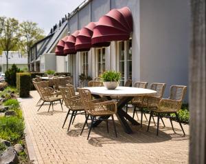 
a patio area with chairs, tables and umbrellas at Hotel De Zeeuwse Stromen in Renesse
