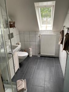 La salle de bains est pourvue de toilettes, d'un lavabo et d'une fenêtre. dans l'établissement Elegantes Apartment, à Wendelstein