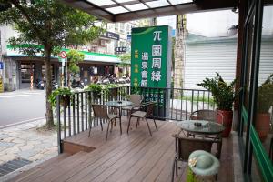 eine Holzterrasse mit Tischen und Stühlen auf einer Straße in der Unterkunft π 園周綠溫泉會館 Pi Hotspring Resort in Jiaoxi