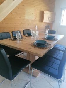 una mesa de madera con sillas, platos y copas de vino en Gîte L'âme Du Gourmand en Pontorson