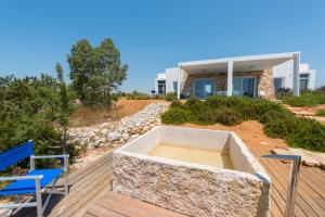 drewniany taras z 2 krzesłami i dom w obiekcie Fani Luxury Villas w mieście Torre Pali