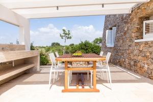 stół i krzesła na patio z kamienną ścianą w obiekcie Fani Luxury Villas w mieście Torre Pali