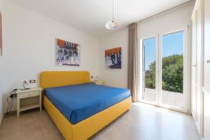 sypialnia z żółtym i niebieskim łóżkiem i oknem w obiekcie Fani Luxury Villas w mieście Torre Pali