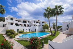 Casa blanca grande con piscina y palmeras en Apartamento Albatros-Son Parc Menorca, en Son Parc