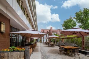 un patio al aire libre con mesas y sombrillas en Gotel Capital, en Beijing