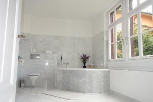 a white bathroom with a tub and a toilet at Bed & Breakfast Grünes Gold am Leisberg in Baden-Baden