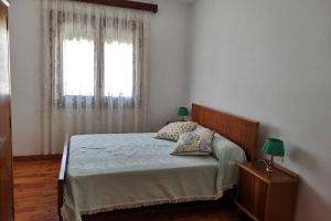 1 dormitorio con 1 cama con 2 lámparas y una ventana en Casa Tía María, en Ansó