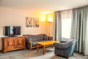 sala de estar con sofá, sillas y TV en Hotel Simonis Koblenz en Coblenza