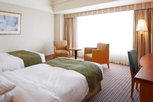 a hotel room with two beds and a desk at JR Hotel Clement Takamatsu in Takamatsu