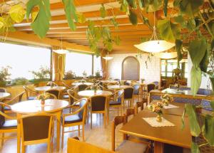 un restaurante con mesas, sillas y ventanas grandes en Piccolo Hotel Sciliar, en Alpe di Siusi