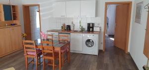uma cozinha com uma mesa e uma máquina de lavar roupa em Ferienhaus-Poweleit em Börgerende-Rethwisch