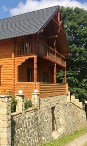 a large log cabin with a stone wall in front at Villa PidStromom in Mykulychyn