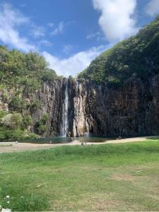 a waterfall on the side of a mountain next to a field at Le Tuit-Tuit **** in Sainte-Suzanne