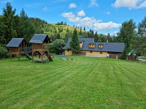 un ampio cortile con una casa e un parco giochi di Palčovka Huty - apartmán U Ondry a U Andělky a Huty