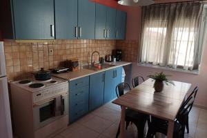 a kitchen with blue cabinets and a table and a stove at Aigli's Urban Lodge in Volos +17 photos
