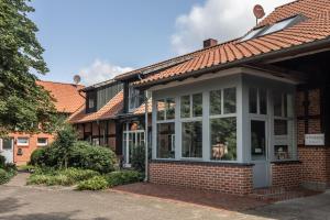 a brick house with a conservatory on the side of it at Pension Cohrs Hof in Hellwege