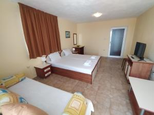 a hotel room with two beds and a television at Guest House Polikseni in Sozopol