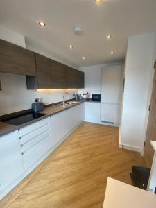 a kitchen with white cabinets and a wooden floor at Whitstable Townhouse by the Sea in Whitstable