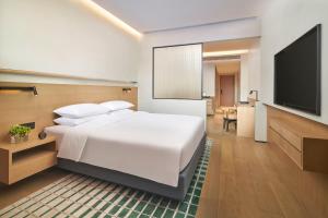 a bedroom with a white bed and a flat screen tv at Hyatt Place Jingdezhen Taoxichuan in Jingdezhen