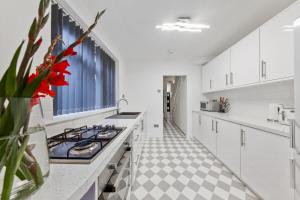 une cuisine avec des placards blancs et une fleur rouge dans un vase dans l'établissement Stunning house, à Londres