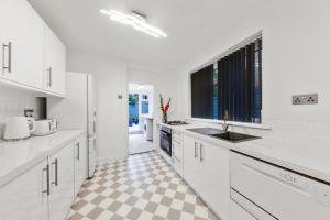 - une cuisine avec des placards blancs et un sol en damier dans l'établissement Stunning house, à Londres
