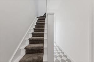 una escalera en una casa con paredes blancas y moqueta en Stunning house, en Londres