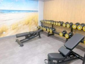 einen Fitnessraum mit Stühlen und ein Gemälde des Strandes in der Unterkunft Apartament Bursztyn Klifowa in Rewal